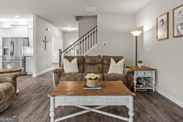 living area featuring dark wood-type flooring, stairway, visible vents, and baseboards