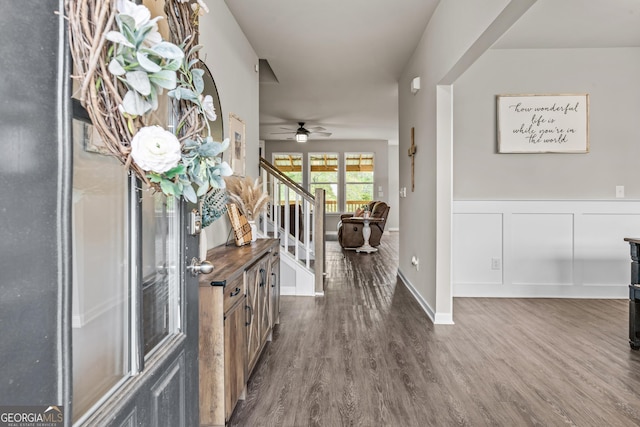hall with wainscoting, dark wood-style flooring, and stairs