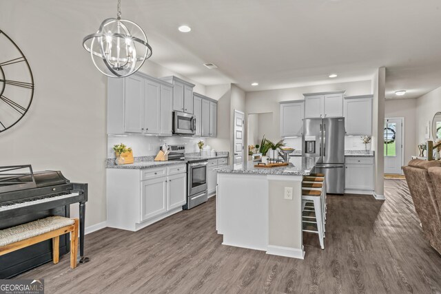 kitchen featuring recessed lighting, dark wood-style floors, a breakfast bar, a center island, and appliances with stainless steel finishes