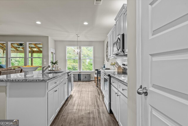 kitchen with light stone counters, dark wood-style flooring, stainless steel appliances, and a sink