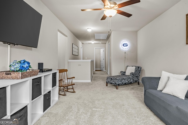 living area featuring attic access, light carpet, a ceiling fan, and baseboards