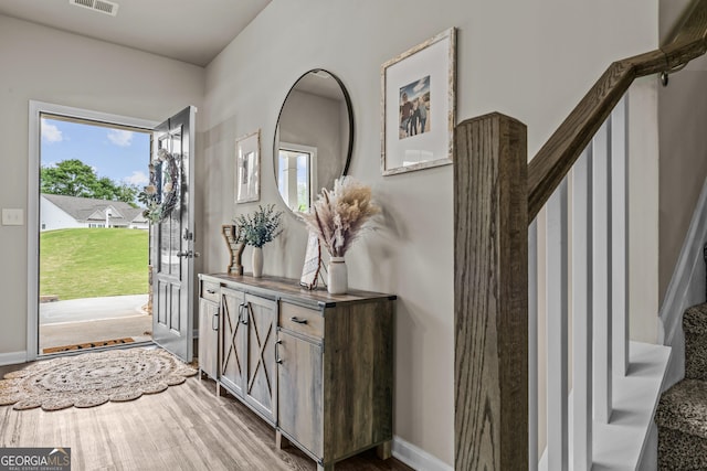 foyer entrance with visible vents, baseboards, and wood finished floors
