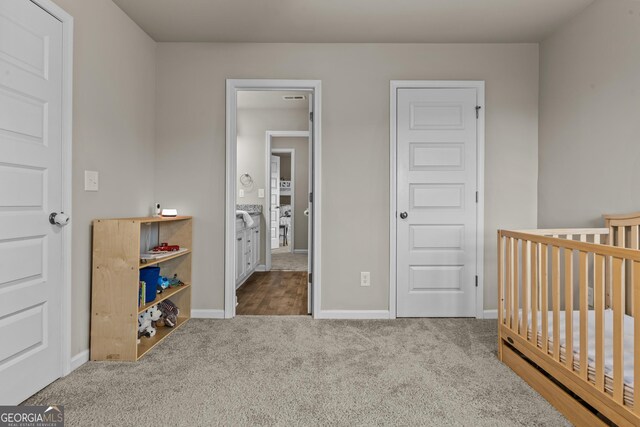 carpeted bedroom featuring a crib and baseboards