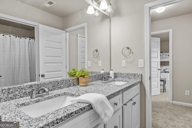 bathroom with double vanity, visible vents, baseboards, and a sink