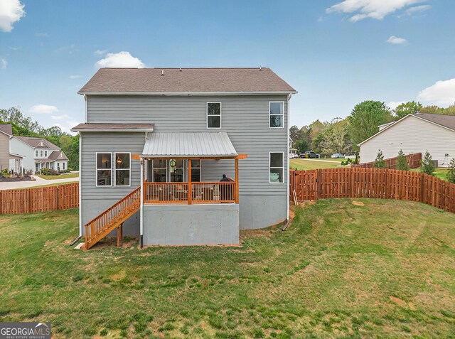 rear view of house with stairway, a fenced backyard, and a yard