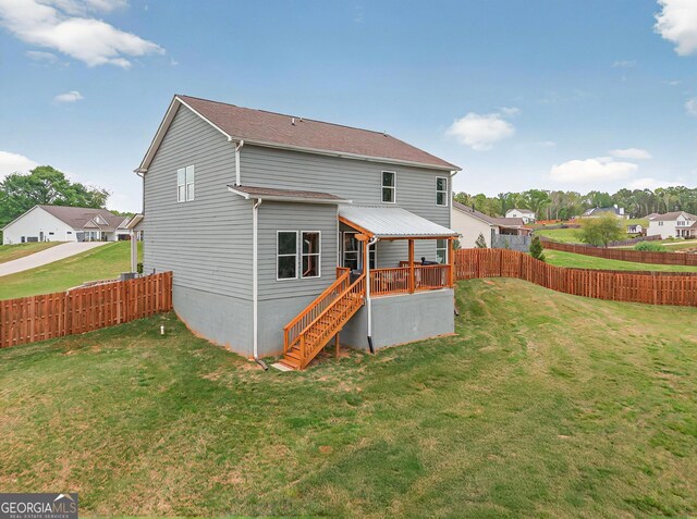back of house with a fenced backyard, a yard, and stairs