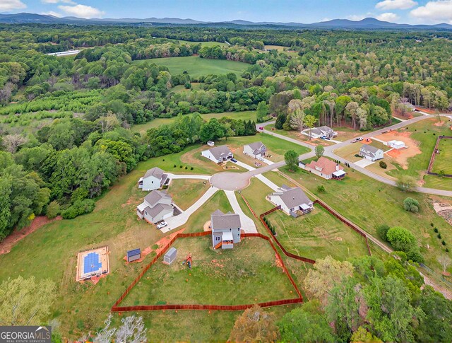 birds eye view of property featuring a mountain view and a wooded view