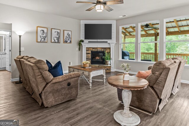 living room with wood finished floors, ceiling fan, a fireplace, baseboards, and visible vents