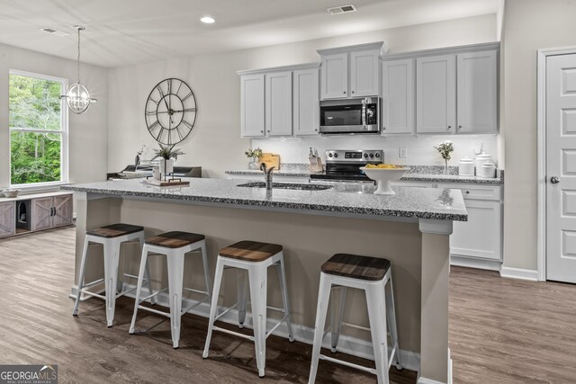 kitchen featuring stainless steel appliances, a kitchen breakfast bar, wood finished floors, and a sink
