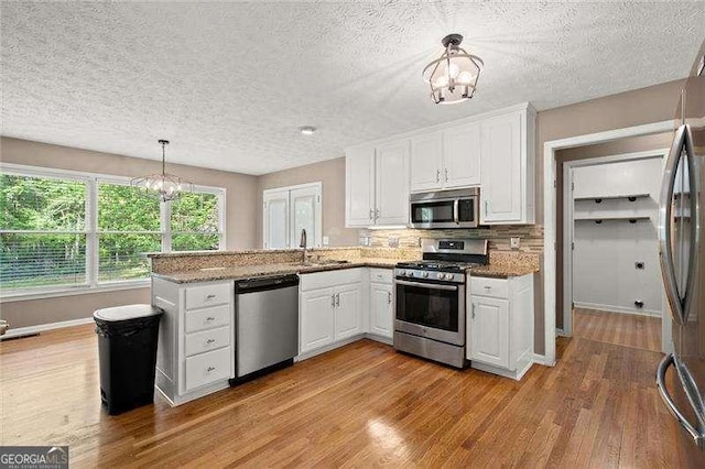 kitchen with white cabinetry, appliances with stainless steel finishes, and a notable chandelier