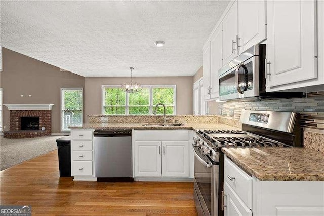 kitchen with stainless steel appliances, a peninsula, a sink, and a textured ceiling