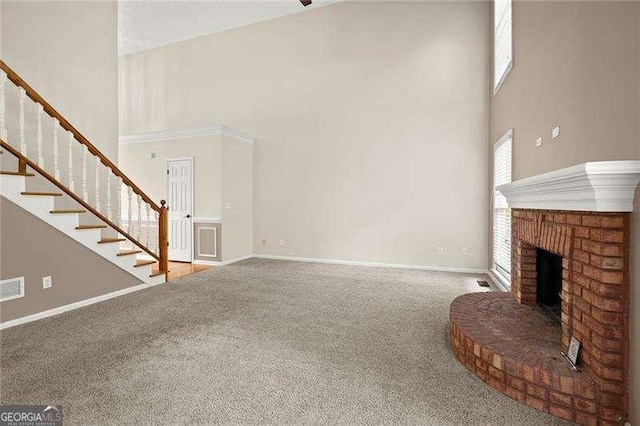 unfurnished living room with baseboards, a high ceiling, carpet floors, and stairway