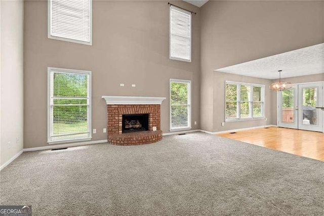 unfurnished living room featuring baseboards, french doors, a towering ceiling, and carpet