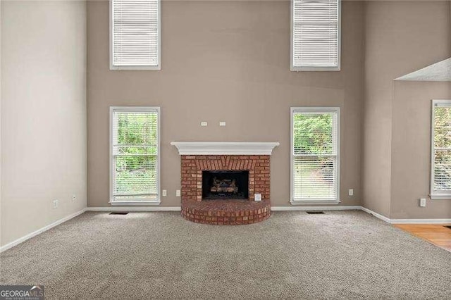unfurnished living room featuring baseboards, a towering ceiling, and a wealth of natural light