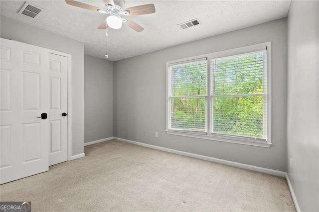 unfurnished bedroom featuring baseboards, visible vents, a textured ceiling, and carpet flooring