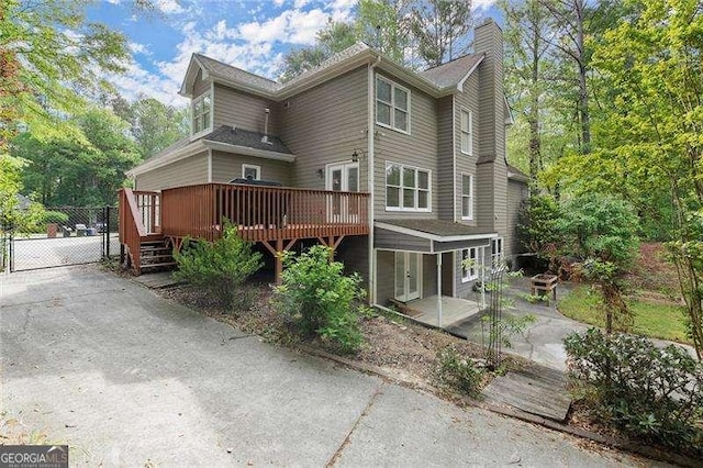 rear view of property with a gate, a chimney, french doors, a patio, and a wooden deck