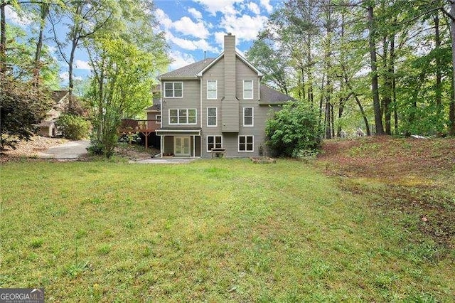back of house with a chimney, a yard, a deck, and french doors