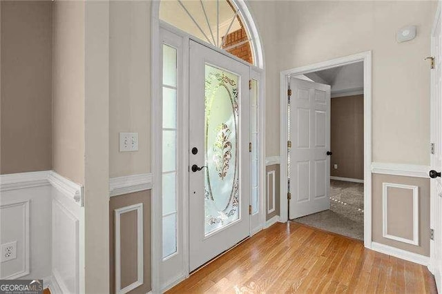 entrance foyer featuring light wood finished floors and a wainscoted wall