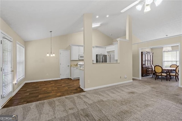 living area featuring carpet floors, baseboards, ceiling fan with notable chandelier, and high vaulted ceiling