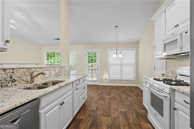 kitchen with light stone countertops, a sink, white cabinets, white appliances, and dark wood-type flooring