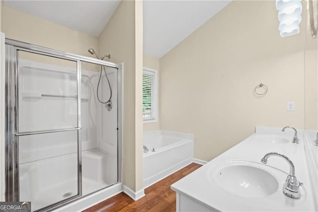 full bath with double vanity, a sink, wood finished floors, and a stall shower