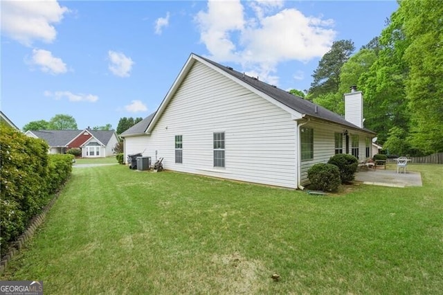 back of property with a lawn, a chimney, a patio area, and central AC