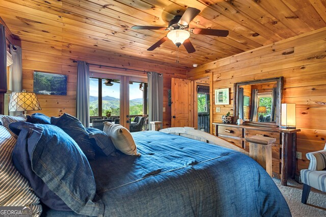 carpeted bedroom featuring french doors, wooden walls, wooden ceiling, and multiple windows
