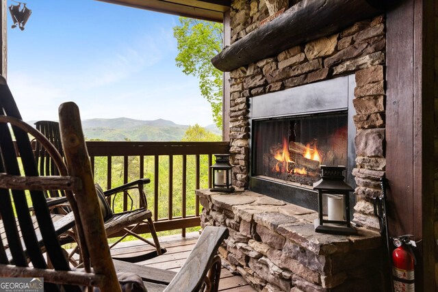deck with an outdoor stone fireplace and a mountain view