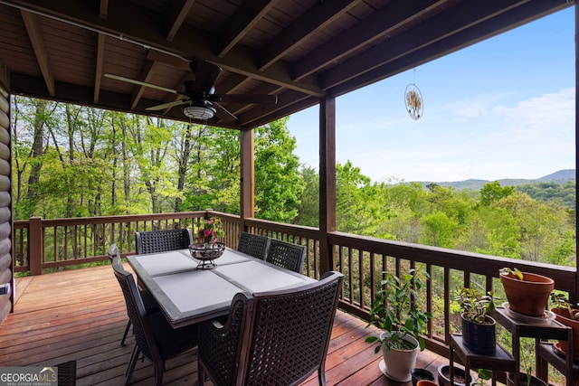 wooden deck featuring outdoor dining area and a wooded view