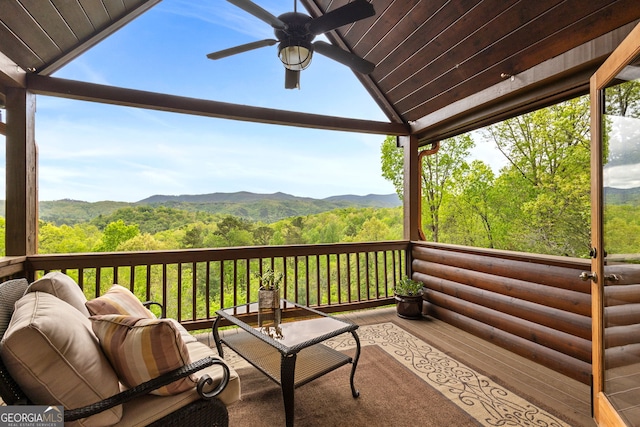 wooden deck with ceiling fan, a wooded view, and a mountain view