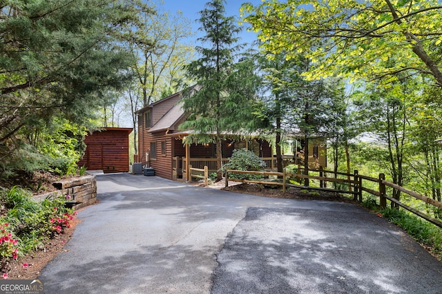 view of front of house featuring aphalt driveway, fence, cooling unit, and a porch
