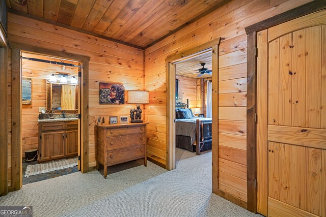 hallway featuring carpet flooring, wooden ceiling, and wood walls