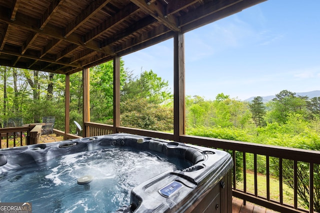 wooden deck featuring a forest view and a hot tub