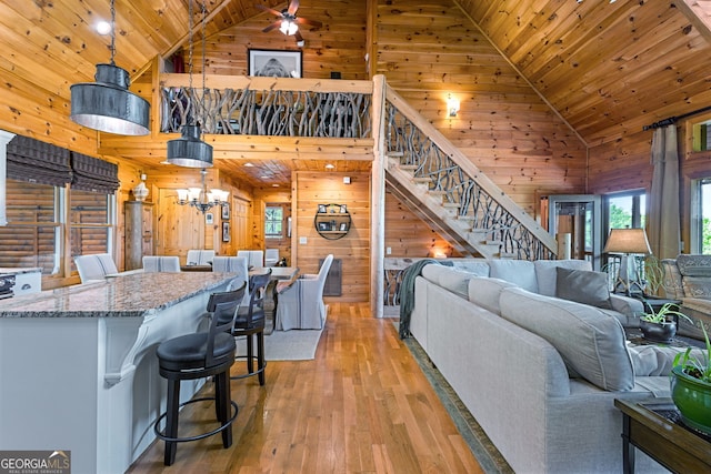 living room with high vaulted ceiling, wooden ceiling, wood walls, and light wood finished floors
