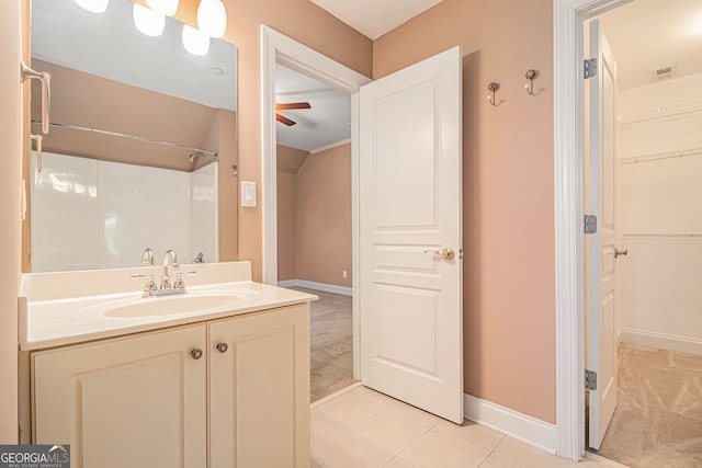 bathroom with a ceiling fan, vanity, baseboards, tile patterned flooring, and a walk in closet