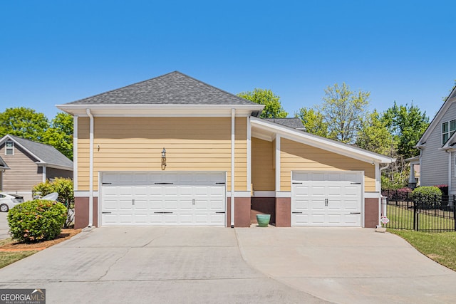 view of front of house with fence, a shingled roof, and concrete driveway