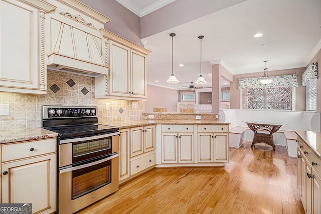 kitchen with double oven range, cream cabinetry, a peninsula, light wood finished floors, and crown molding