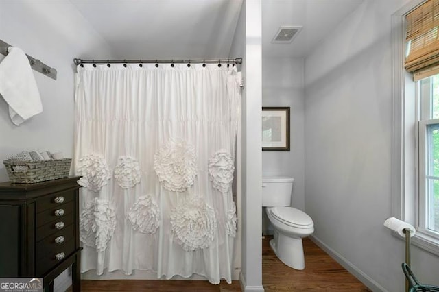 bathroom with toilet, baseboards, visible vents, curtained shower, and wood finished floors