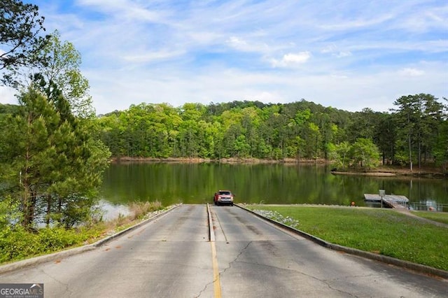 view of dock with a wooded view and a water view