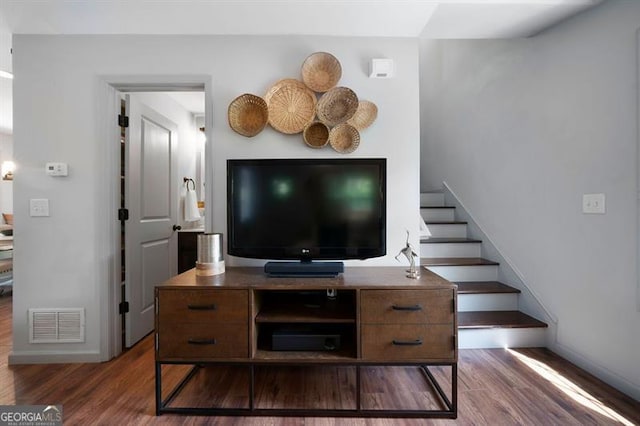 living area with baseboards, stairs, visible vents, and wood finished floors