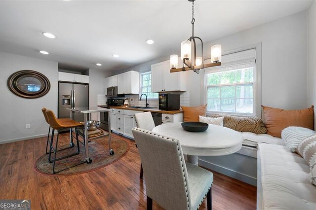 dining area with dark wood finished floors, a chandelier, baseboards, and recessed lighting