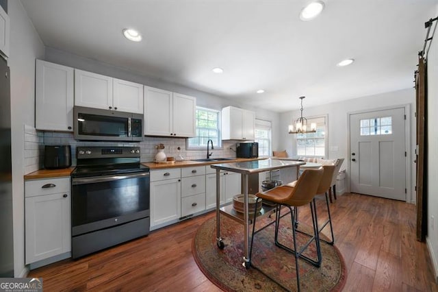 kitchen with a sink, wood counters, black / electric stove, white cabinets, and stainless steel microwave