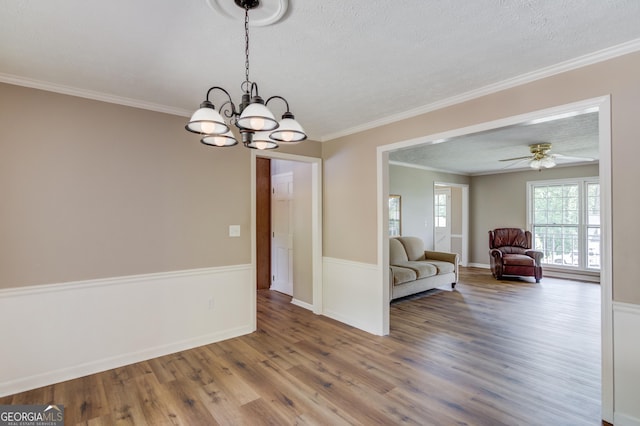 interior space featuring wood finished floors, a textured ceiling, baseboards, and ornamental molding