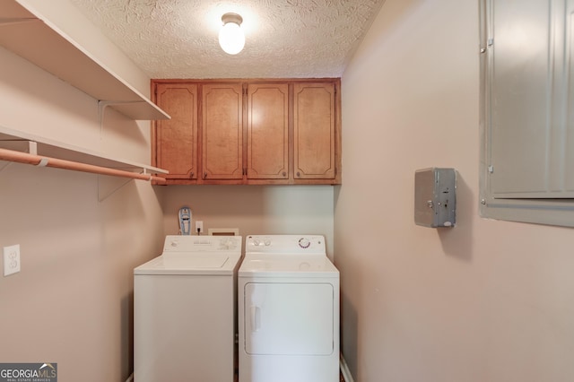 washroom featuring cabinet space, washer and clothes dryer, a textured ceiling, and electric panel