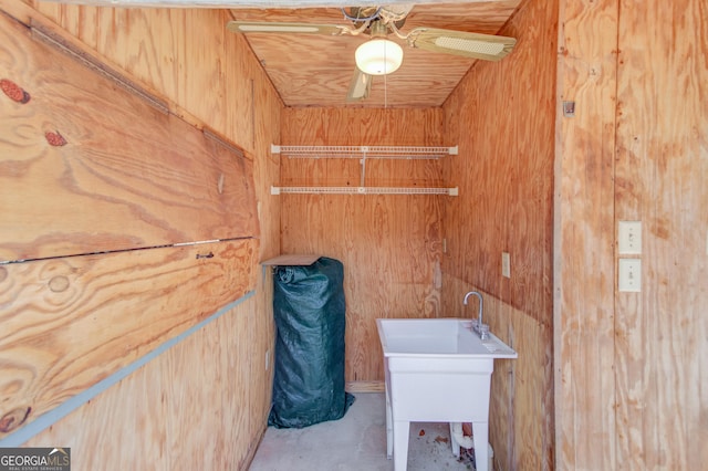 clothes washing area featuring wood walls and a ceiling fan
