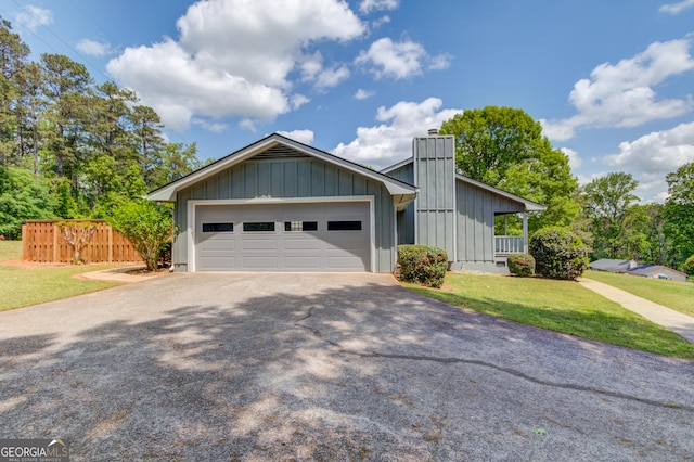view of front of house with a chimney, aphalt driveway, fence, a front lawn, and board and batten siding