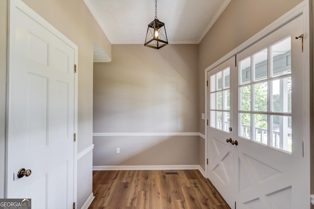 doorway with visible vents, wood finished floors, baseboards, and ornamental molding