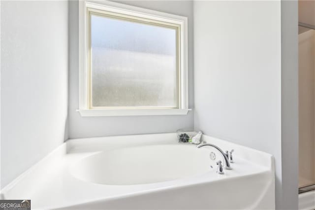 bathroom with plenty of natural light and a bath