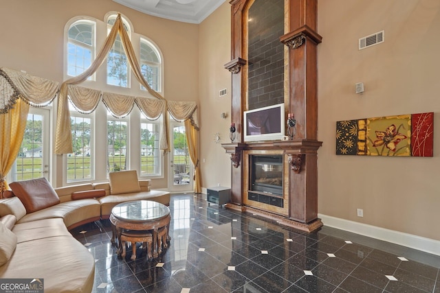 living area with granite finish floor, a towering ceiling, a large fireplace, and baseboards