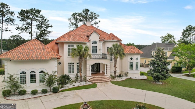 mediterranean / spanish house with a chimney, a balcony, a tile roof, and stucco siding